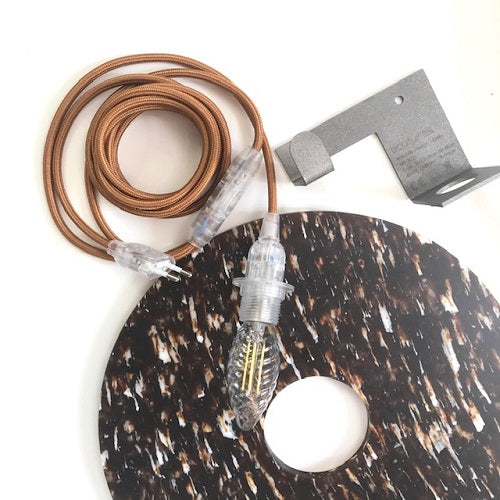 Applique murale en plastique recyclé ronde posée à côté de son support métallique et de sa douille avec son câble et l'ampoule