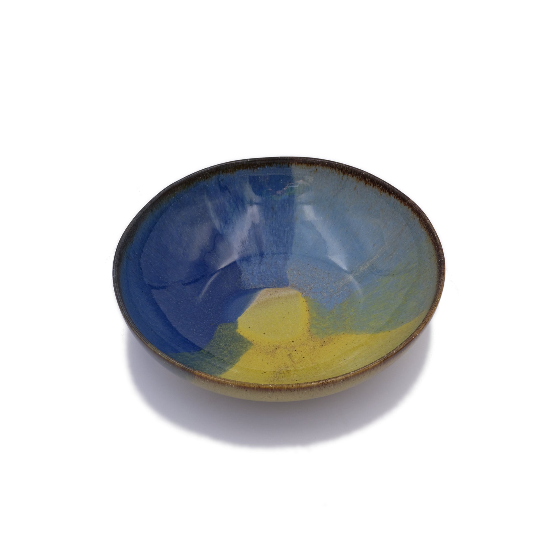 vue en biais, assiette creuse en grès naturel avec motif tricolore bleu profond, bleu ciel et jaune
