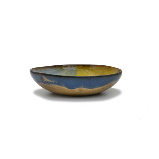 vue de profil, assiette creuse en grès naturel avec motif tricolore bleu profond, bleu ciel et jaune