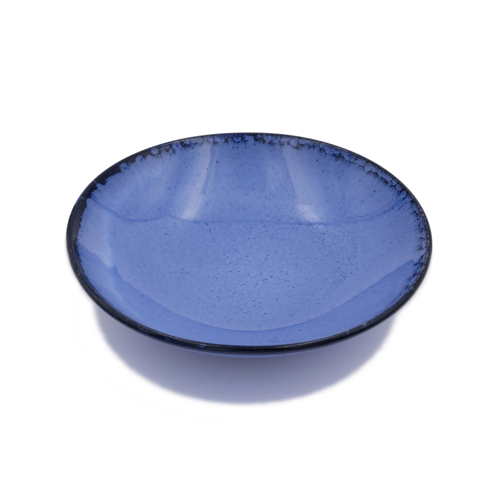 vue de biais, assiette creuse en grès naturel et émail réactif bleu profond